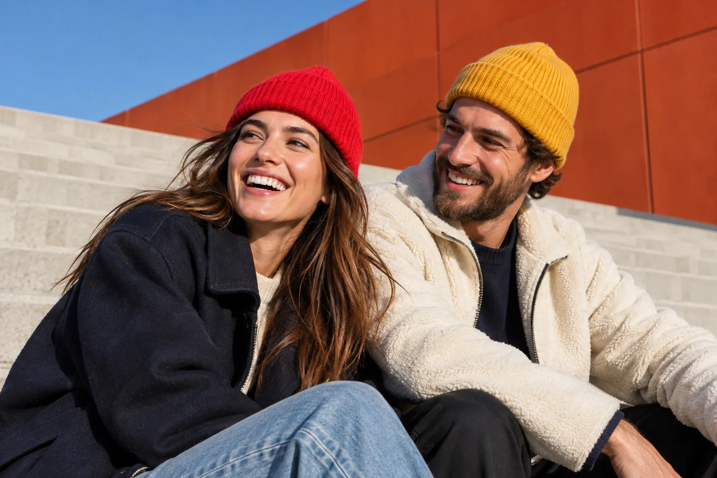 Streetstyle-Inspiration: zwei Erwachsene mit rotem und gelbem Umschlag-Beanie auf urbanen Betontreppen